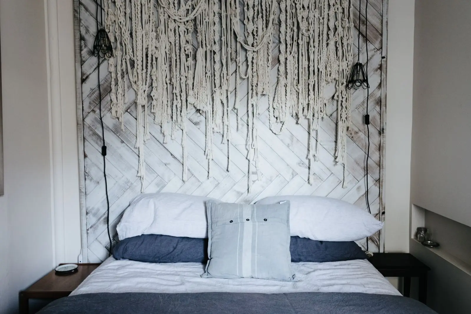 Bedroom with a made bed against a textured headboard wall